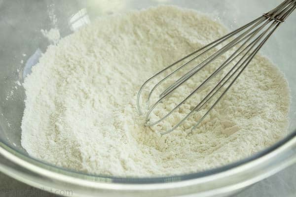 Flour and salt in clear bowl with whisk