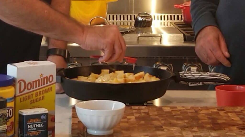 Fried apples in a pan with ingredients being added