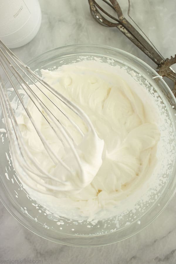 Homemade whipped cream in a bowl with whisk