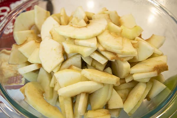 Cored, peeled and sliced apples in a clear bowl