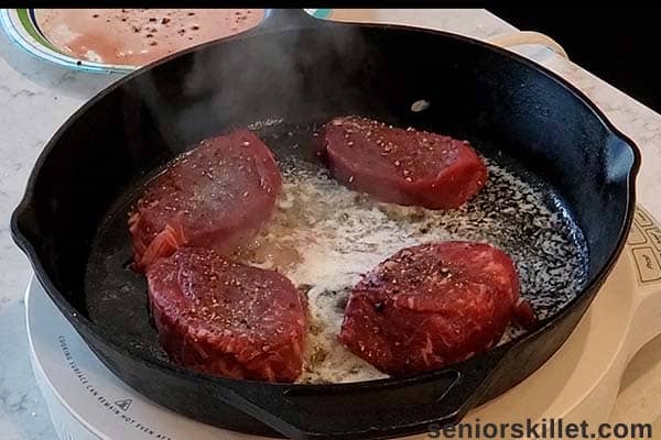 raw tenderloins in a cast iron pan
