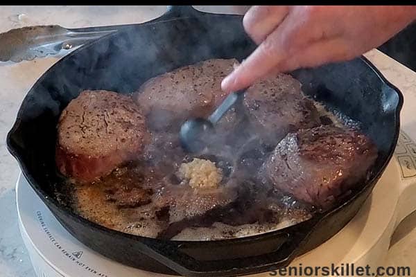 Garlic added to pan with steaks