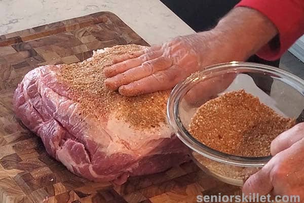 Adding rub to the pork butt