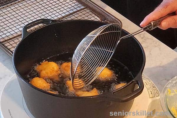 Removing fried hush puppies from pan