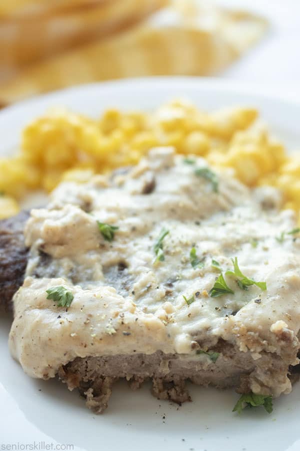 Cut cube steak on a plate with gravy and corn.